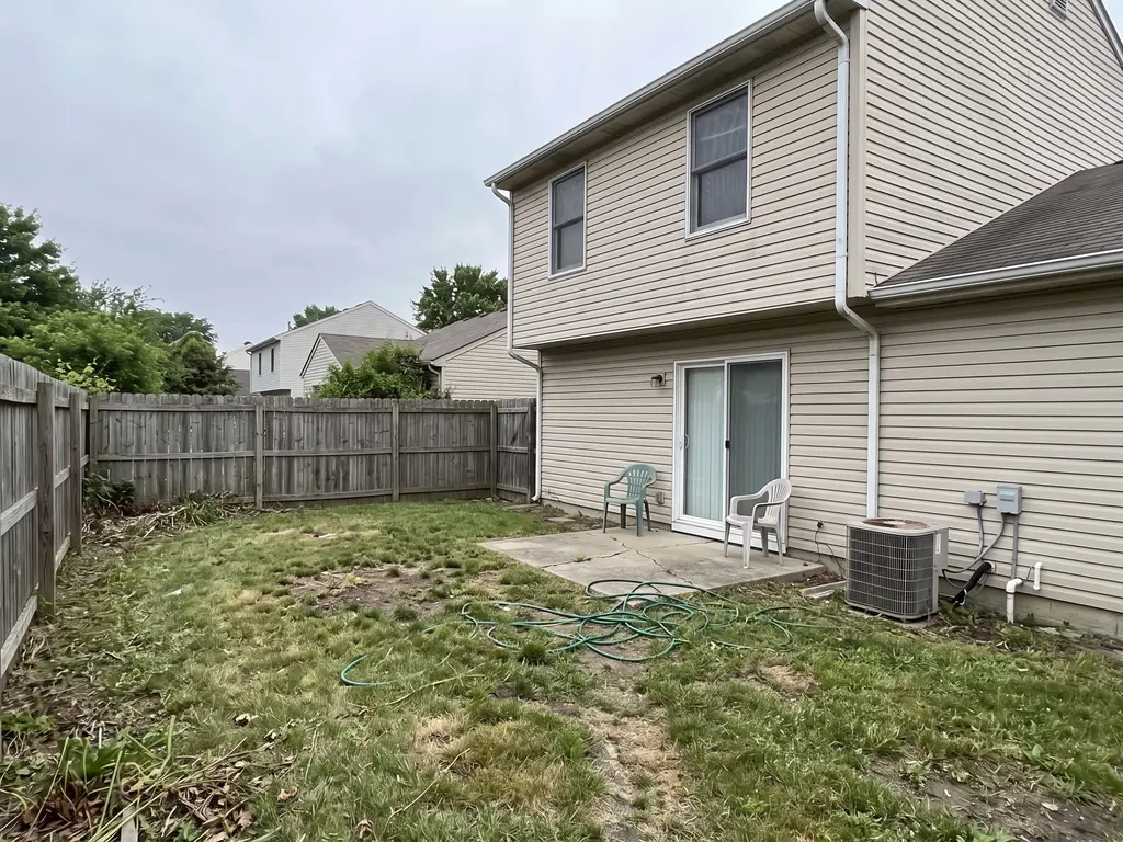 The Millers' backyard today: patchy lawn, cracked slab, wooden fence